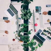 Twee mensen werken tegenover elkaar aan bureaus. Van bovenaf gefotografeerd.