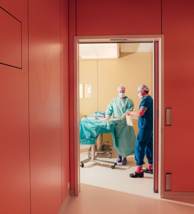 Twee OK-medewerkers achter een openstaande deur.