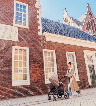 Vrouw loopt achter een kinderwagen in de stad.