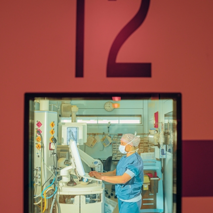 Een OK-medewerker achter een deur met een glas