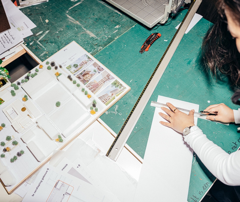 Een architect is achter een tekentafel aan het werk.