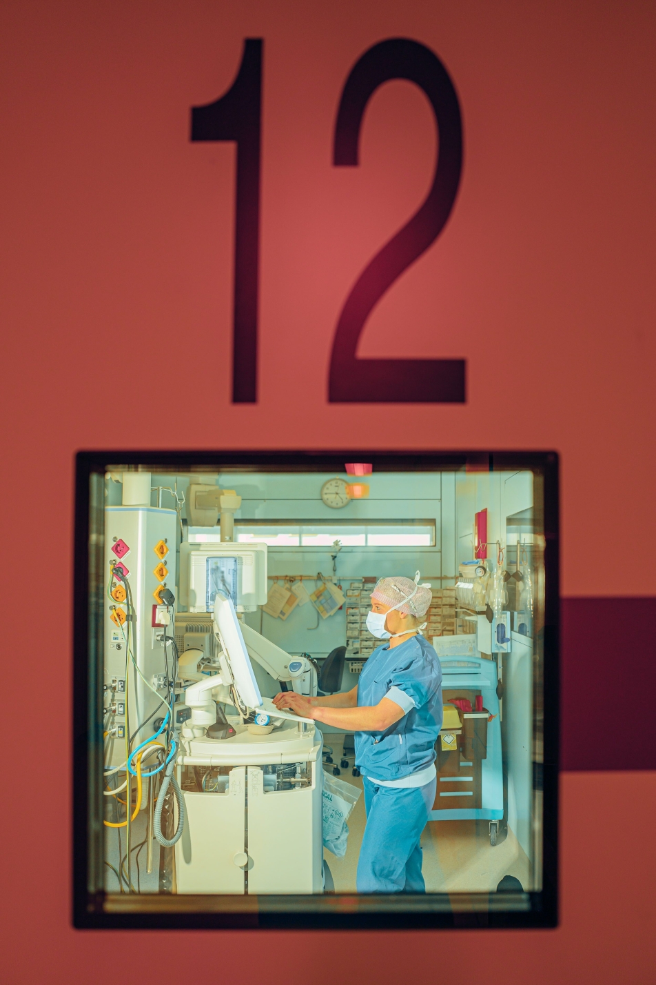 Een OK-medewerker achter een deur met een glas