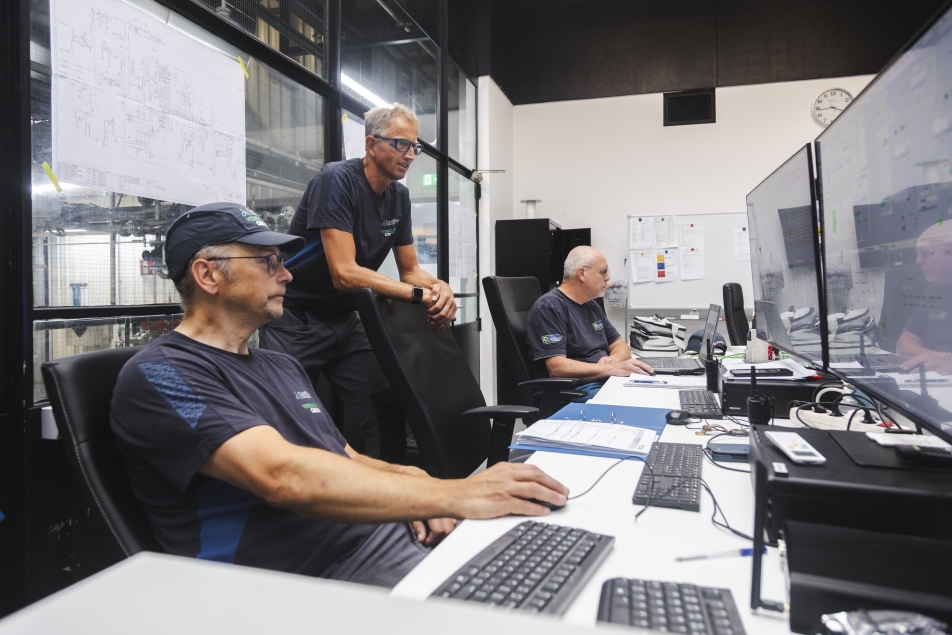 Drie medewerkers houden achter hun desk de systemen en het leidingwerk in de gaten.